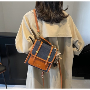 Detail of color-block backpack with denim and brown leather featuring a plush bunny charm