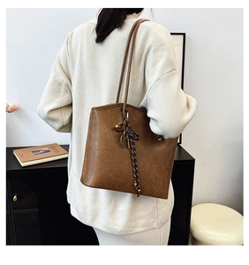 Side view of a vintage brown leather tote bag with braided charm for work commuting