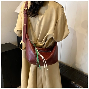 Macro detail of wine red crescent bag with adjustable wide leather strap and tassel