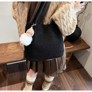 Détail du cabas en polaire noire avec un pendentif en fausse fourrure blanche et poupée
