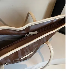 Detail of smooth metal zipper and curved embossed texture on brown tote bag
