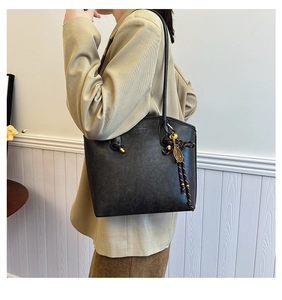 Close-up of black retro tote bag with textured leather and decorative metallic charms