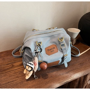 Close-up of light blue handbag with cute bear charm and brown leather brand tag detail