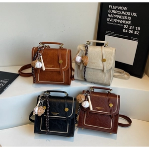 Detail view of four vintage leather crossbody bags with baseball keychains and gold rivets