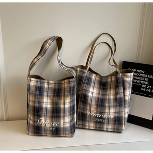 Détail de sacs cabas à carreaux en toile avec deux types de anses et texte graphique