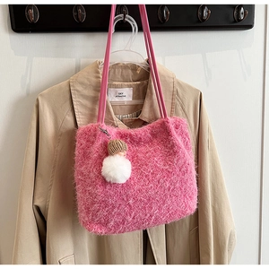 Détail d'un sac cabas en peluche rose avec texture douce et breloque pompon blanc
