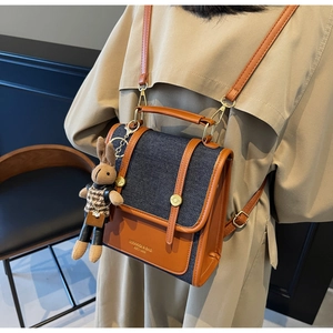 Retro denim and brown leather backpack detail with a cute plush bunny charm on the side