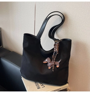 Détail d'un sac cabas en daim noir avec bandoulière en cuir et breloque teckel marron