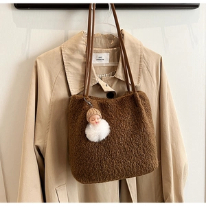 Détail du sac cabas marron en peluche avec un pendentif poupée et des anses sombres