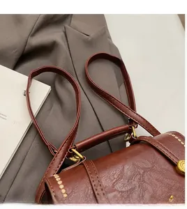 Close-up of brown vintage leather bag with gold hardware and smooth shoulder strap