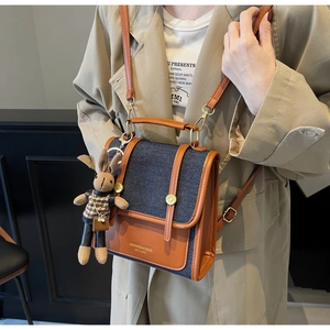 Close-up of retro denim patchwork bag with brown leather details and cute bunny charm