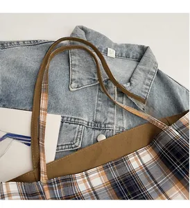 Gros plan détaillé d'un sac cabas en toile à carreaux avec anses marron sur du denim
