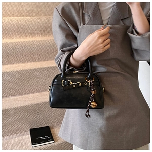 Détail du sac à main rétro noir avec ornements dorés et pendentif cloche élégant