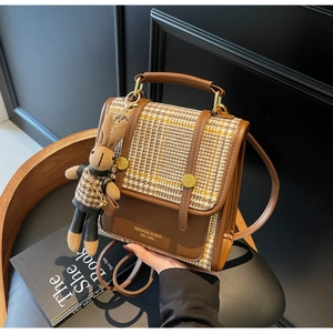 Detail of tweed and leather patchwork backpack with a rabbit plush pendant and metal lock