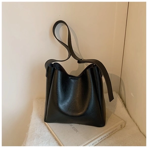 Detail view of the wide adjustable leather strap and polished finish on the black bucket bag