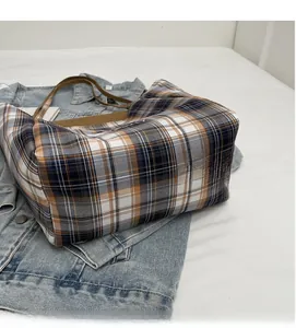Gros plan d'un sac cabas à carreaux colorés avec des poignées marron sur denim