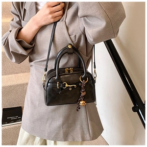 Détail d'un sac à main vintage en cuir noir mat avec fermeture éclair dorée et breloque