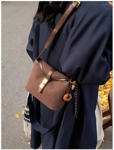 Close-up of vintage brown matte crossbody bucket bag with gold clasp and tassel detail