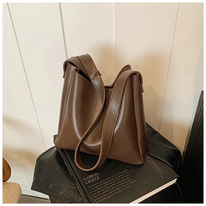 Close-up of soft brown leather bucket bag texture and straps on vintage book prop