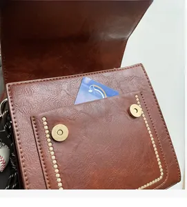 Detail of brown vintage leather bag showing magnetic gold snaps and interior pocket storage