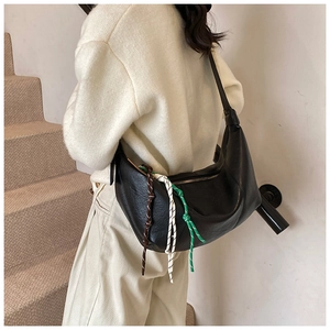 Detail of black leather hobo bag featuring decorative multi-color braided rope charms