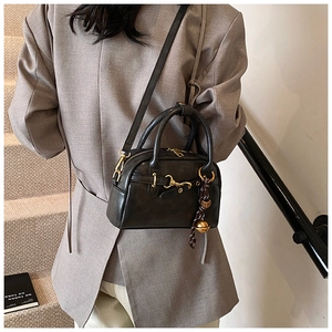Détail d'un petit sac bandoulière noir vintage avec finitions dorées porté par un mannequin