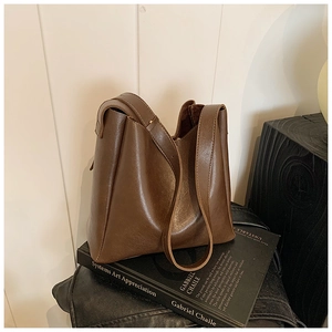 Detail view of smooth dark brown vintage faux leather material on a bucket shoulder bag