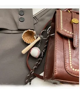 Detail of baseball theme keychain with leather glove and bat on a brown briefcase