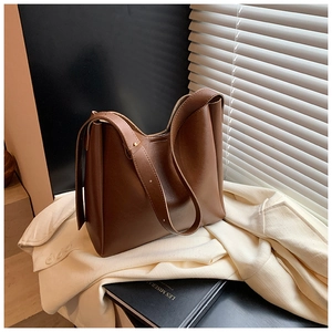 Detailed texture of dark brown leather bucket bag with matte finish and wide strap