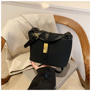 Close-up of black bucket bag with gold square twist lock and canvas leather texture
