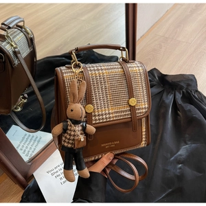 Detail of retro plaid mini backpack with leather trim and cute rabbit plush charm