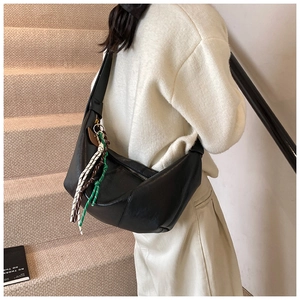 Detail of a black leather crescent hobo bag with colorful woven tassel ornaments