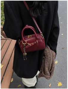 Sac bandoulière vintage bordeaux en cuir avec finitions dorées en extérieur automnal