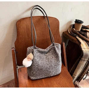 Sac fourre-tout en maille grise sur une chaise en bois avec un charme de poupée