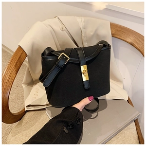 Detail of black matte bucket bag featuring a golden twist lock and adjustable strap