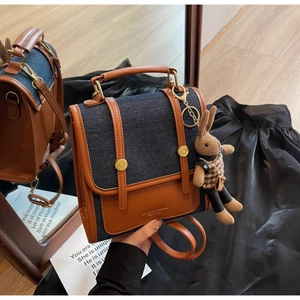 Detail of retro denim patchwork backpack with brown leather trim and cute rabbit charm