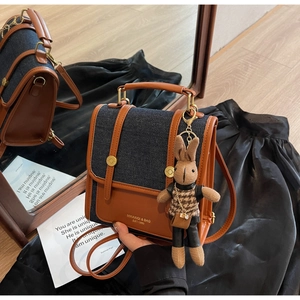 Detail of retro color-block denim backpack with brown leather trim and rabbit charm