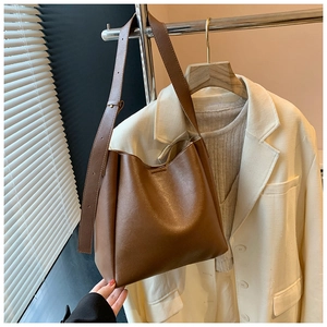 Detailed view of brown PU leather tote bag with adjustable strap on white blazer