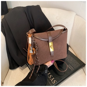 Close-up of brown frosted suede bucket bag with gold metal buckle and woven charm detail