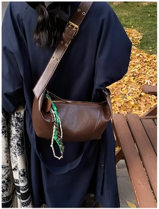 Detail of dark brown crescent bag featuring smooth oil wax leather and woven strap detail