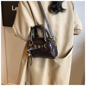 Vue détaillée du sac polochon en cuir PU marron chocolat avec zip doré et breloque cloche