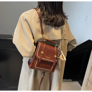 Detail of vintage dark brown faux leather bag with white contrast stitching and gold hardware