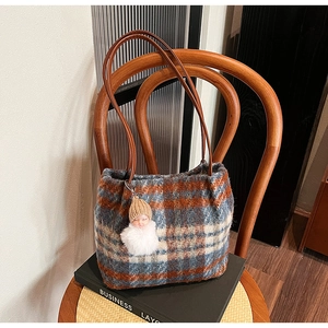 Détail d'un sac à bandoulière en laine à carreaux avec lanière en cuir et pendentif