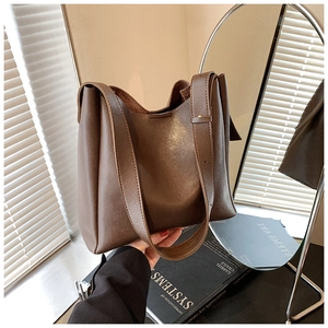 Detailed view of dark brown leather tote bag with wide strap on minimalist art books