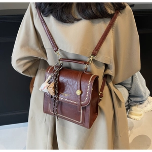 Detail of vintage brown PU leather backpack with contrast stitching and bear charm
