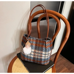 Détail d'un sac cabas en laine à carreaux vintage avec pompon et breloque poupée