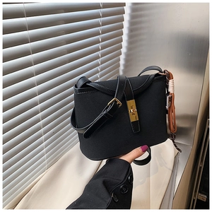 Detail of black matte bucket bag with gold twist lock and woven tassel pendant strap
