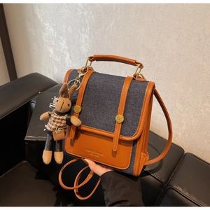 Detail of denim and leather patchwork crossbody bag with a cute rabbit charm