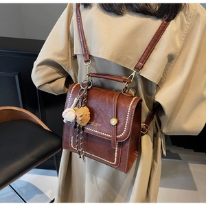 Detail of brown leather backpack with contrast stitching and baseball pendant