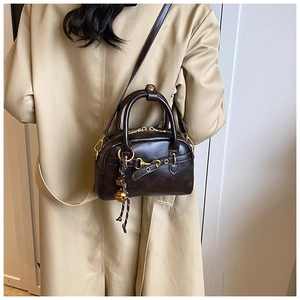 Detail of dark brown vintage Boston bag with gold zipper and ball pendant on a model